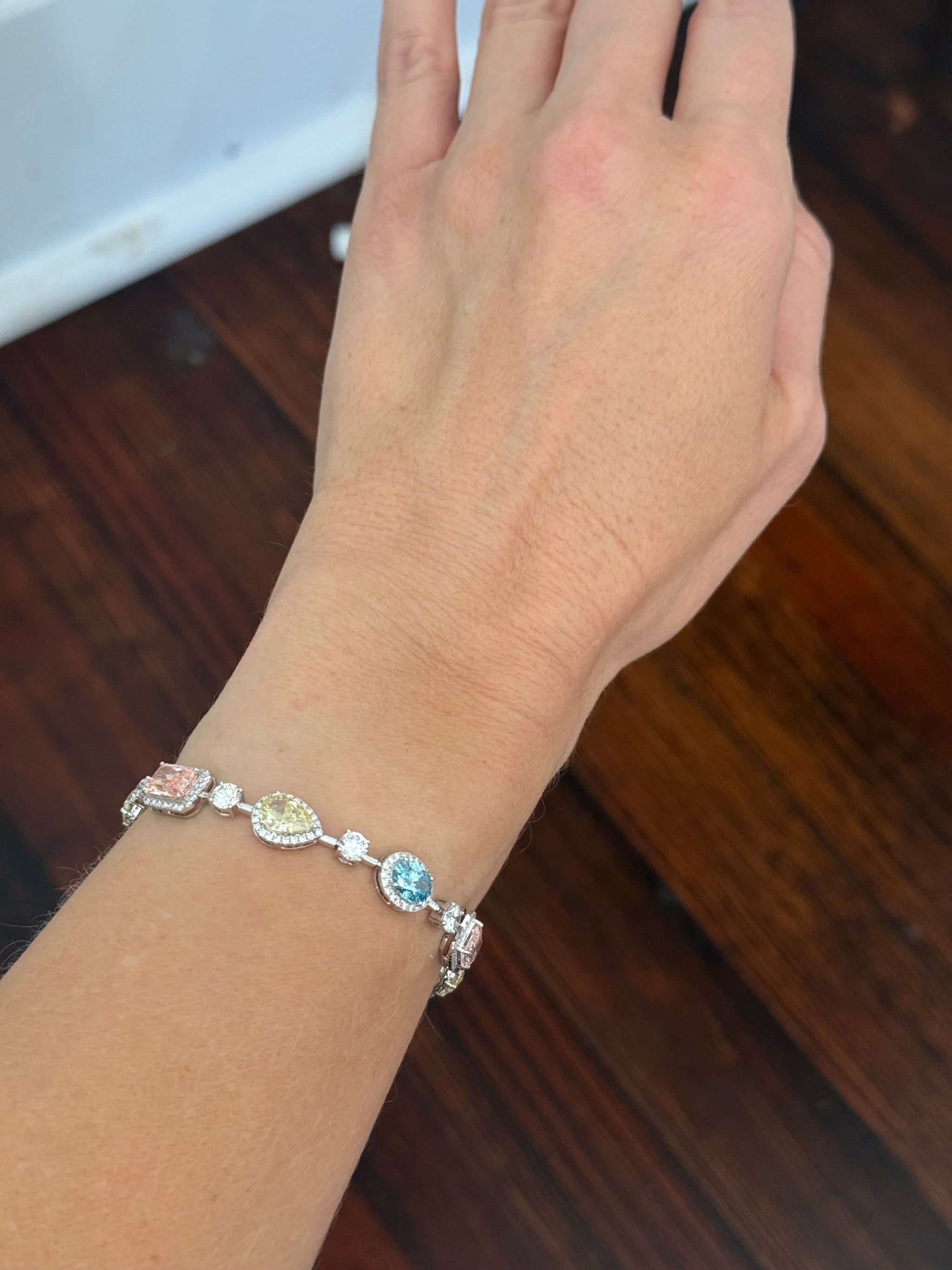 White gold mixed shape bracelet with radiant and marquise pink lab diamonds, oval blue lab diamonds, oval cushion and pear shaped yellow lab diamonds, and round white lab diamonds