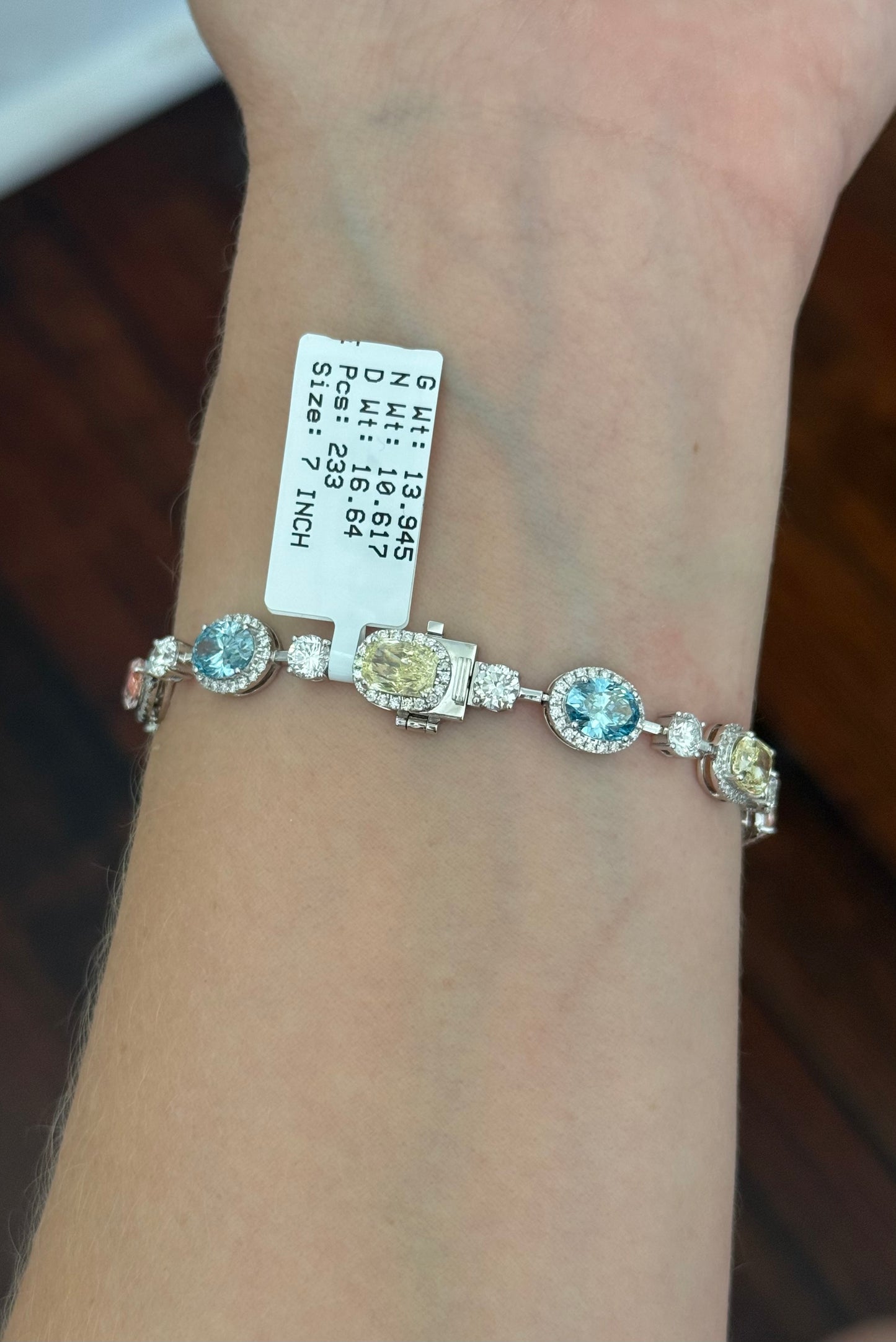 White gold mixed shape bracelet with radiant and marquise pink lab diamonds, oval blue lab diamonds, oval cushion and pear shaped yellow lab diamonds, and round white lab diamonds