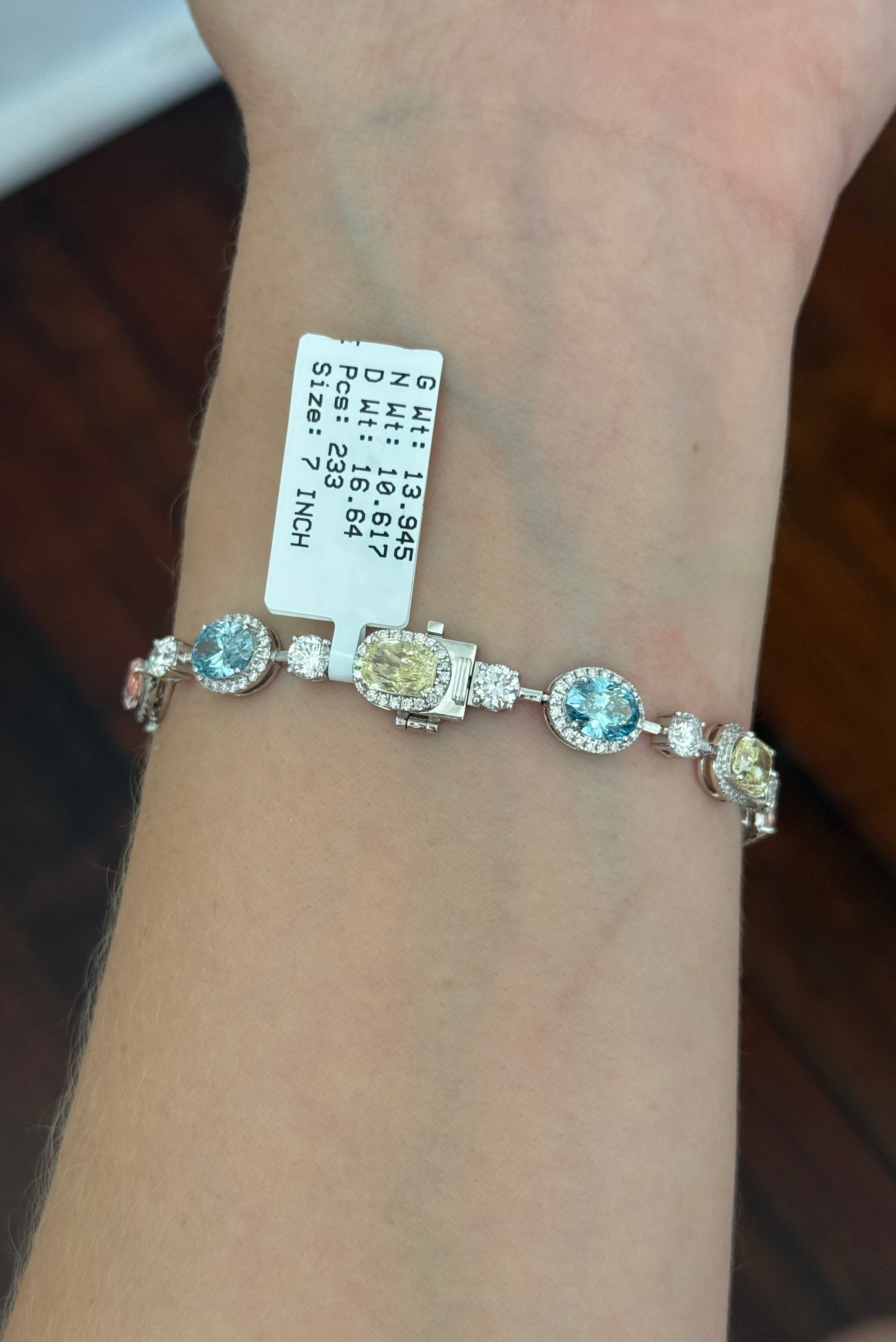 White gold mixed shape bracelet with radiant and marquise pink lab diamonds, oval blue lab diamonds, oval cushion and pear shaped yellow lab diamonds, and round white lab diamonds