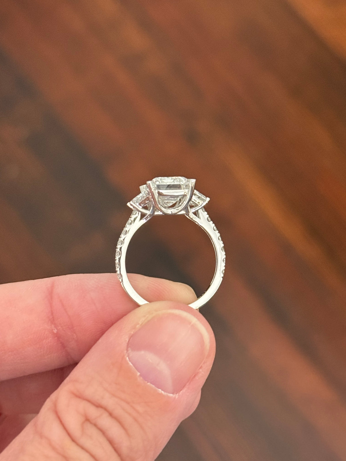 White gold emerald cut, trapezoid, and round lab diamond ring. Center stone is 4.06cts