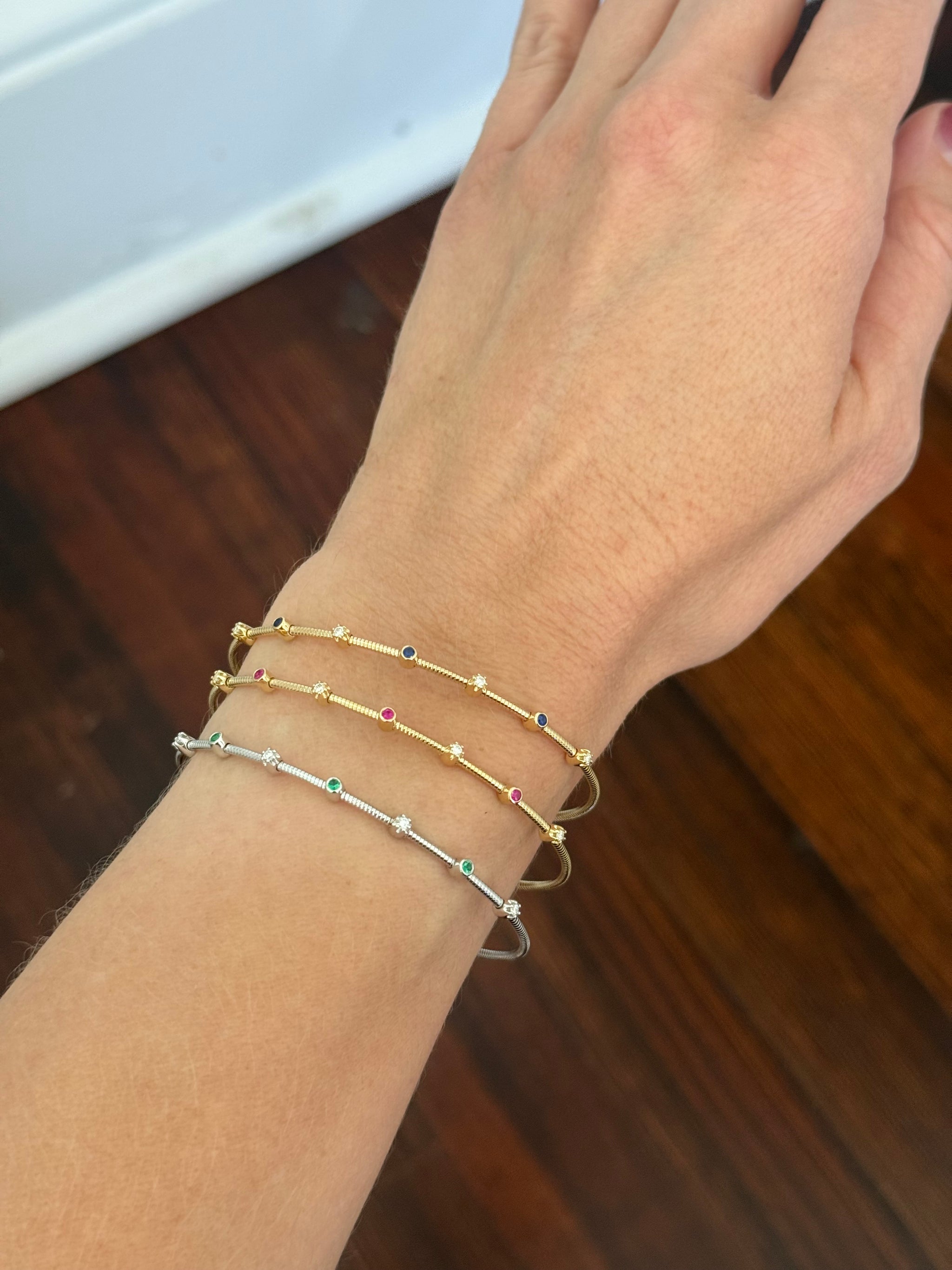 Natural diamond flex bracelets available in yellow gold with sapphires, yellow gold with rubies, and white gold with emeralds